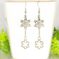 Long Chain and Snowflakes Charm Earrings displayed on a tea cup.