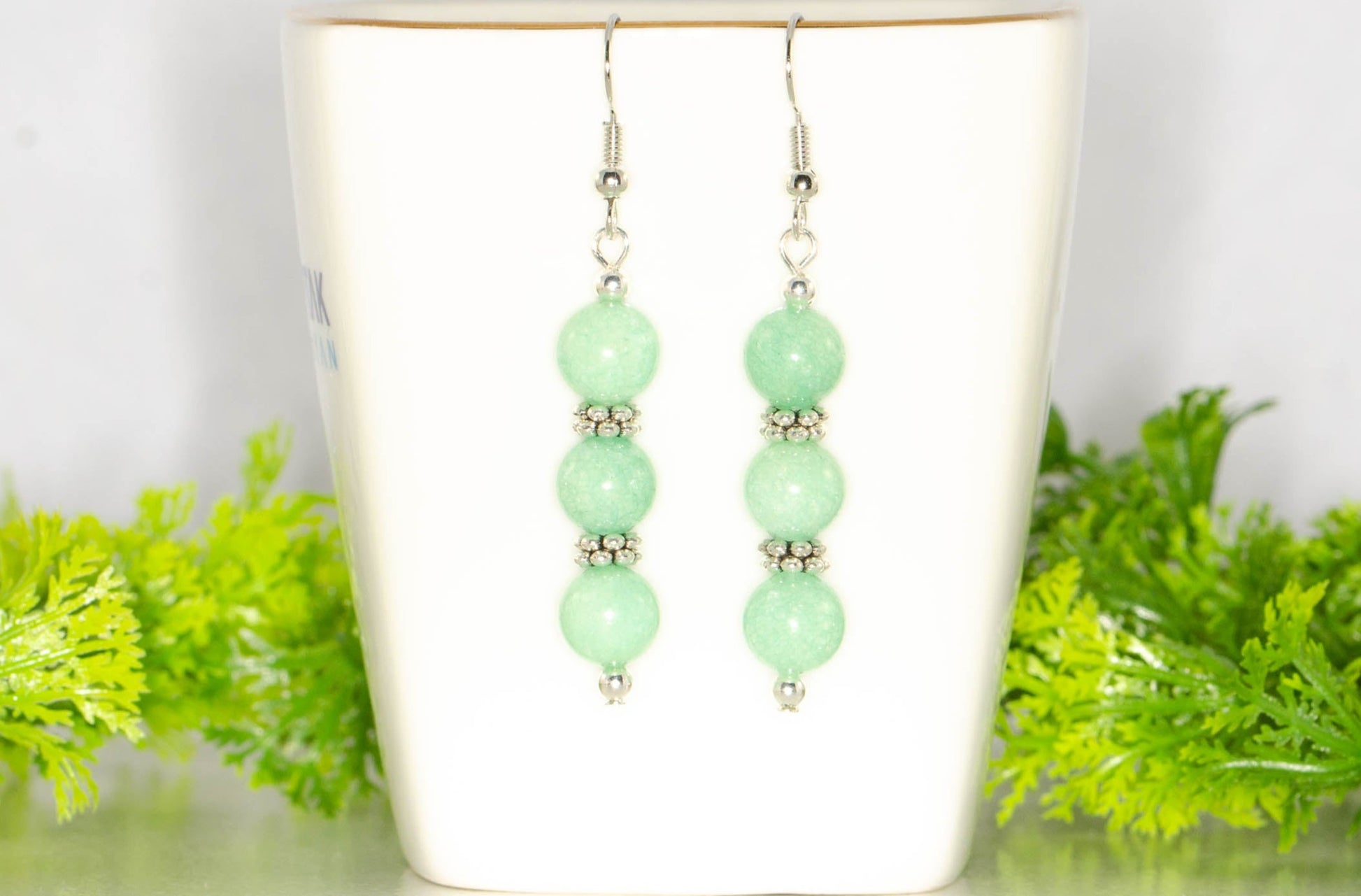 Natural Mint Green Quartz Beaded Bar Earrings displayed on atea cup.