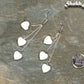 Long Silver Plated Chain and Seashell Heart Earrings beside a dime.