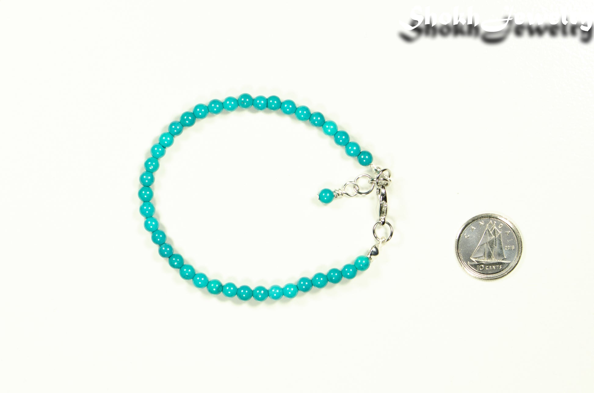 4mm Turquoise Stone Bracelet with Clasp beside a dime.