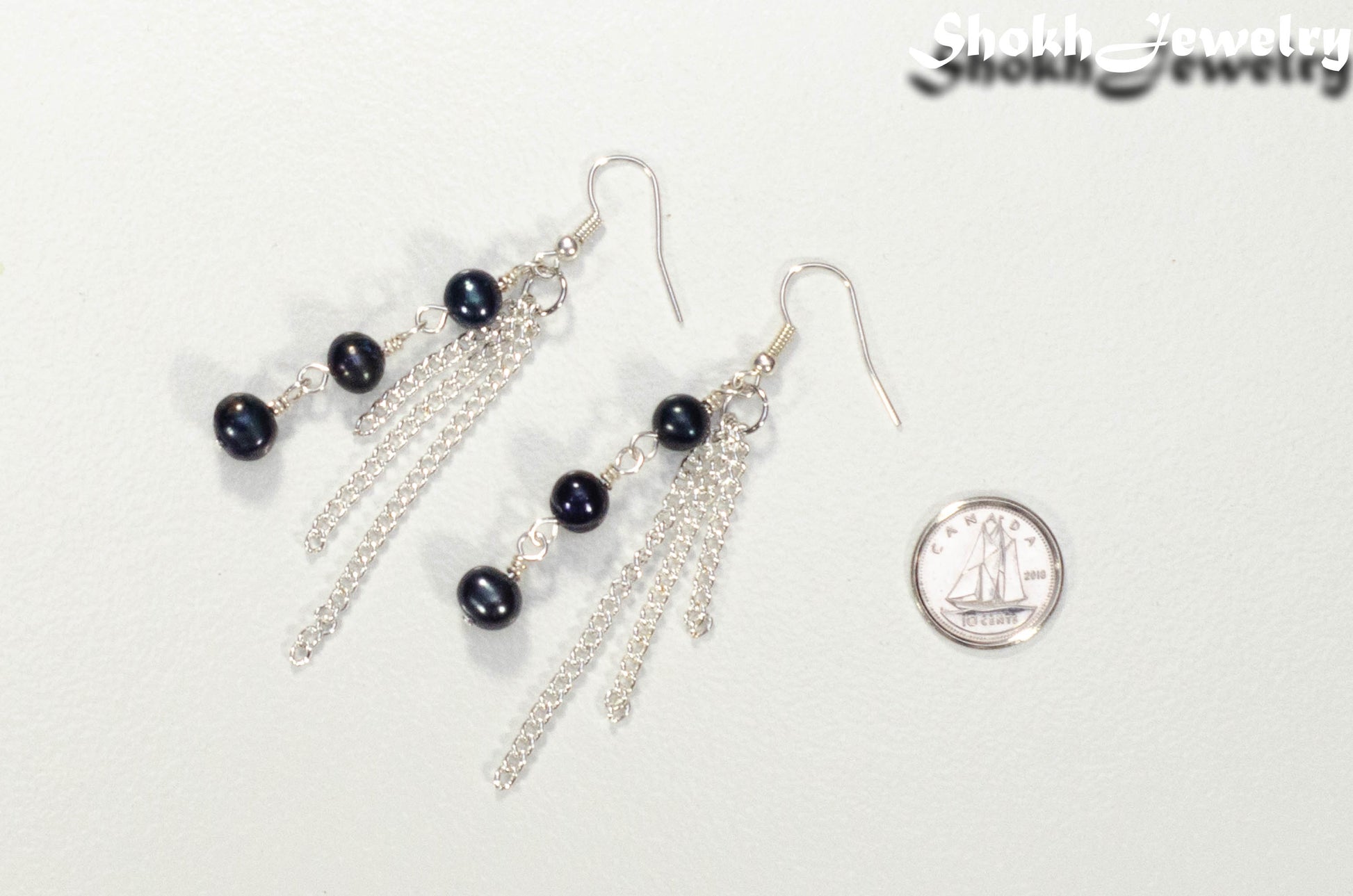 Long Chain and Black Freshwater Pearls Earrings beside a dime.