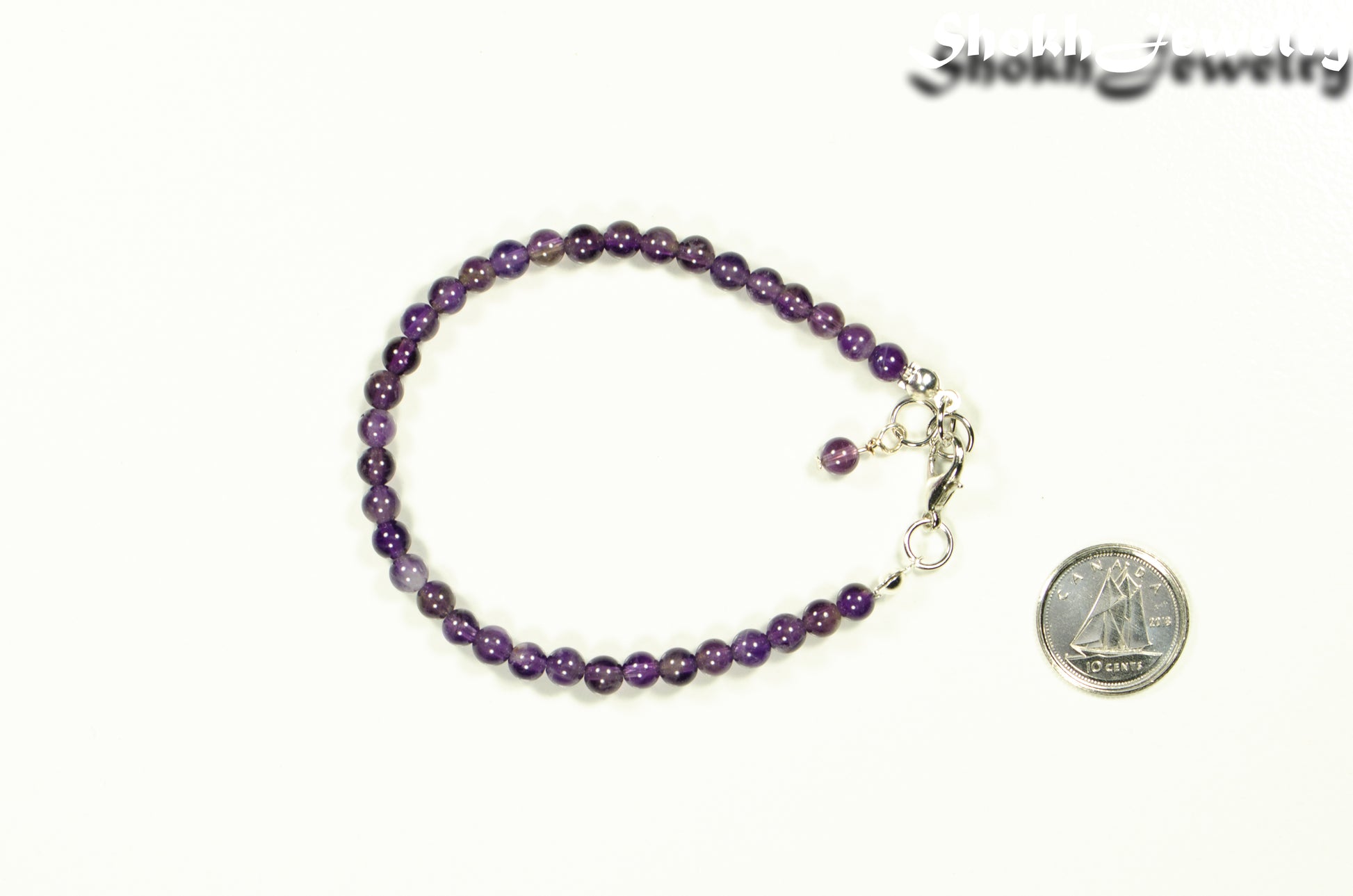 4mm Amethyst Bracelet with Clasp beside a dime.