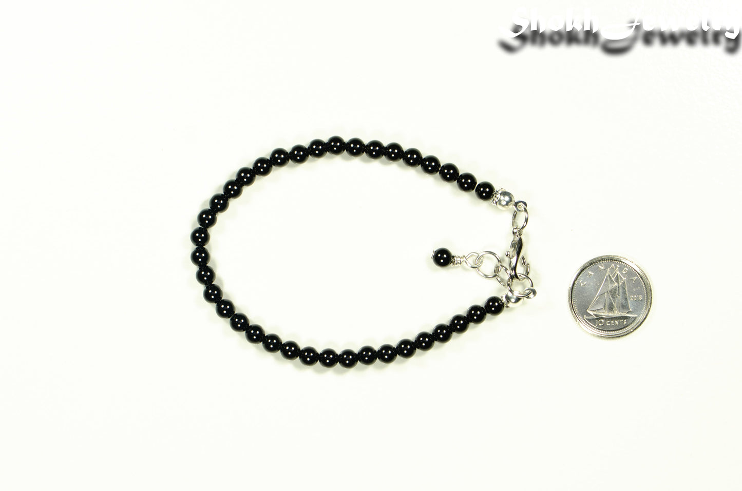4mm Black Obsidian Crystal Bracelet with Clasp beside a dime.
