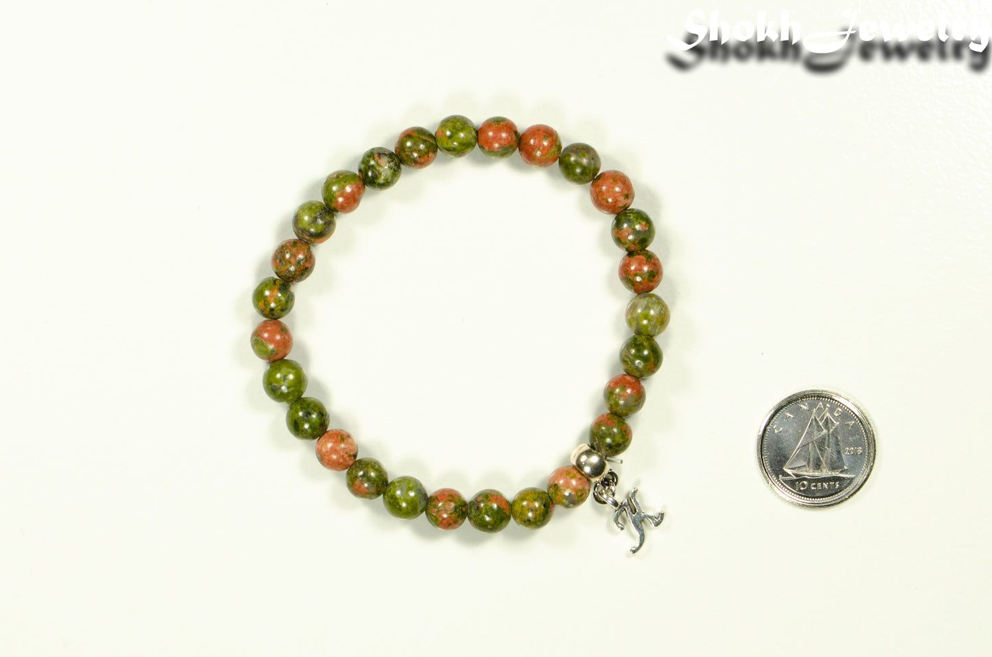 6mm Unakite Bracelet with Initial beside a dime.