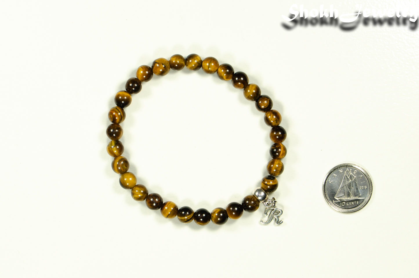 6mm Tiger's Eye Bracelet with Initial beside a dime.