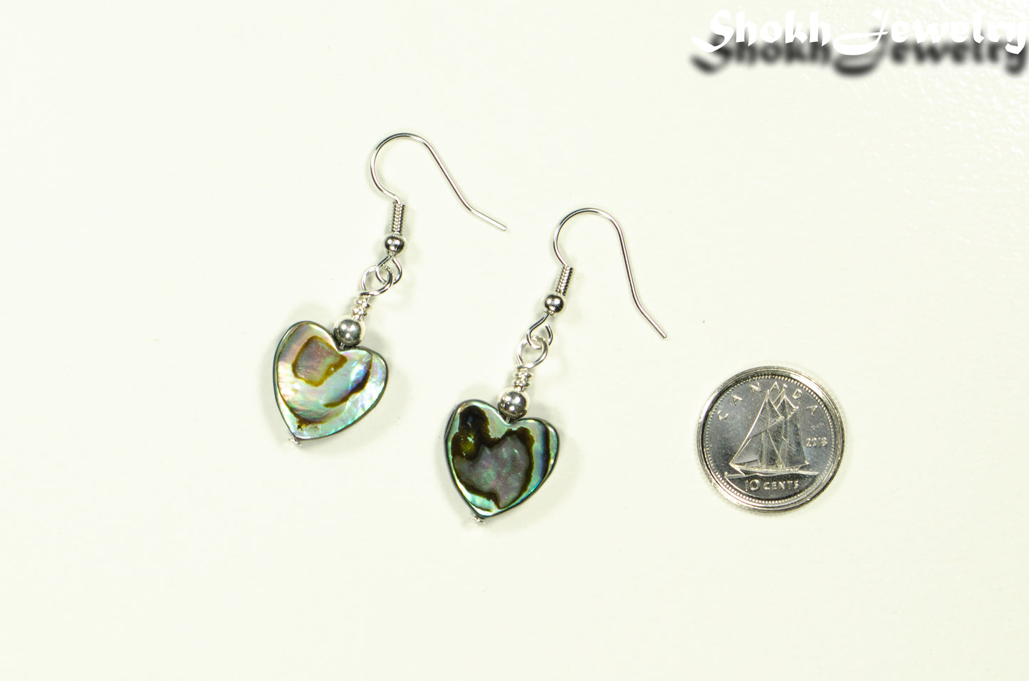 Heart Shaped Abalone Shell Earrings beside a dime.
