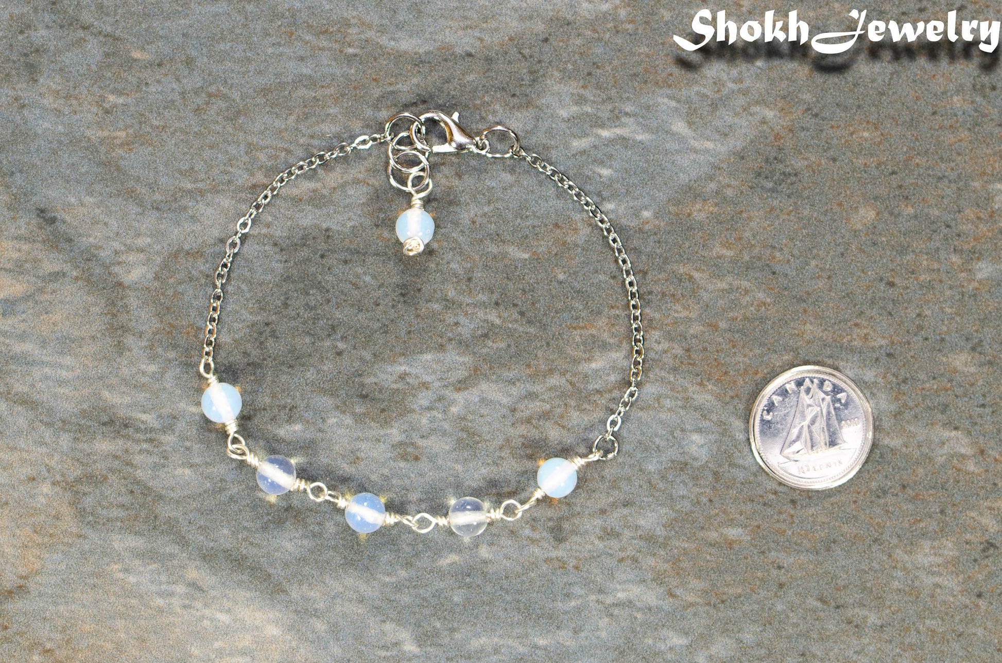 White Opal and Stainless Steel Chain Bracelet beside a dime.