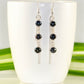 Long Chain and Black Freshwater Pearls Earrings displayed on a coffee mug.