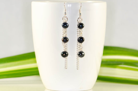 Long Chain and Black Freshwater Pearls Earrings displayed on a coffee mug.