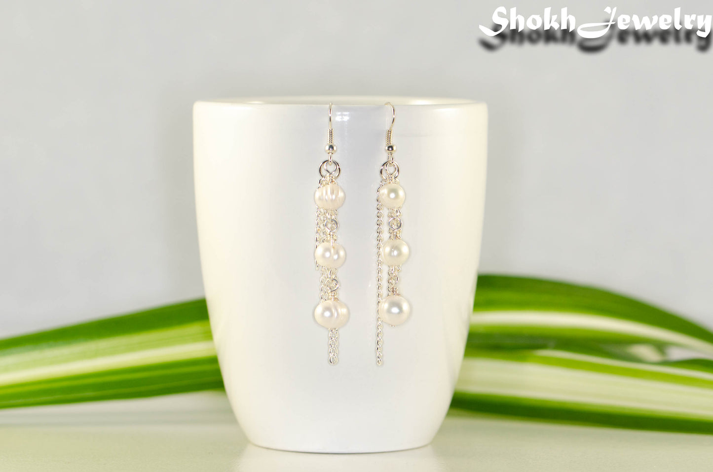 Long Chain and Freshwater Pearls Earrings displayed on a coffee mug.