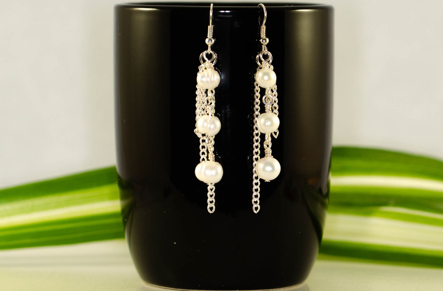 Long Chain and Freshwater Pearls Earrings displayed on a coffee mug.