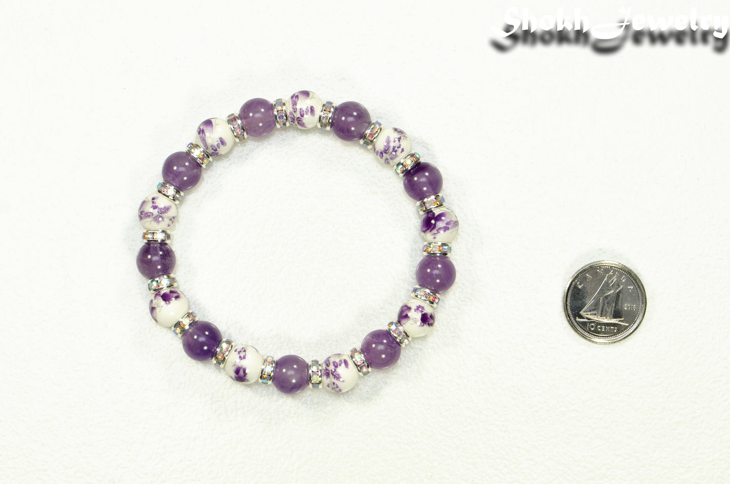 Amethyst and Purple Flower Ceramic Bead Bracelet besude a dime.