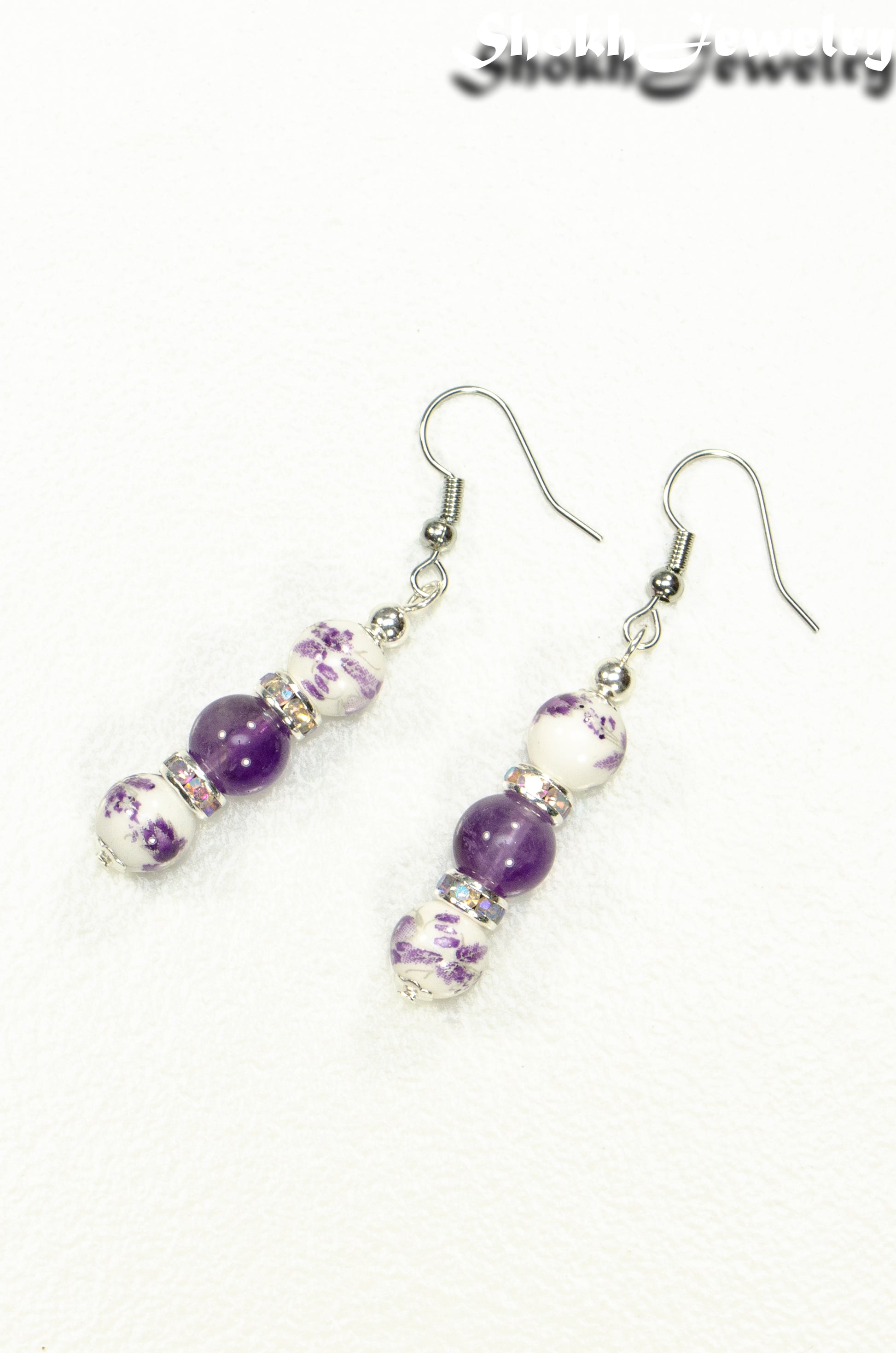 Top view of Long Floral Ceramic Bead and Amethyst Earrings.
