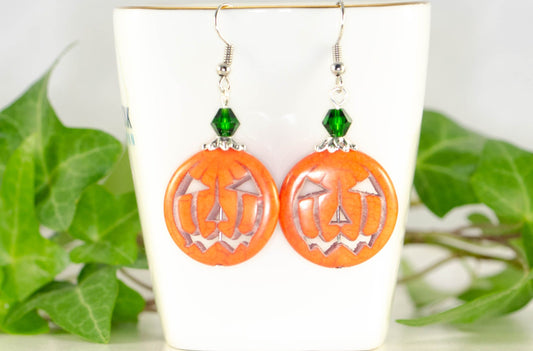 Spooky Halloween Pumpkin Earrings displayed on a tea cup.