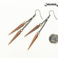 Long chain and antique copper spike earrings beside a dime.