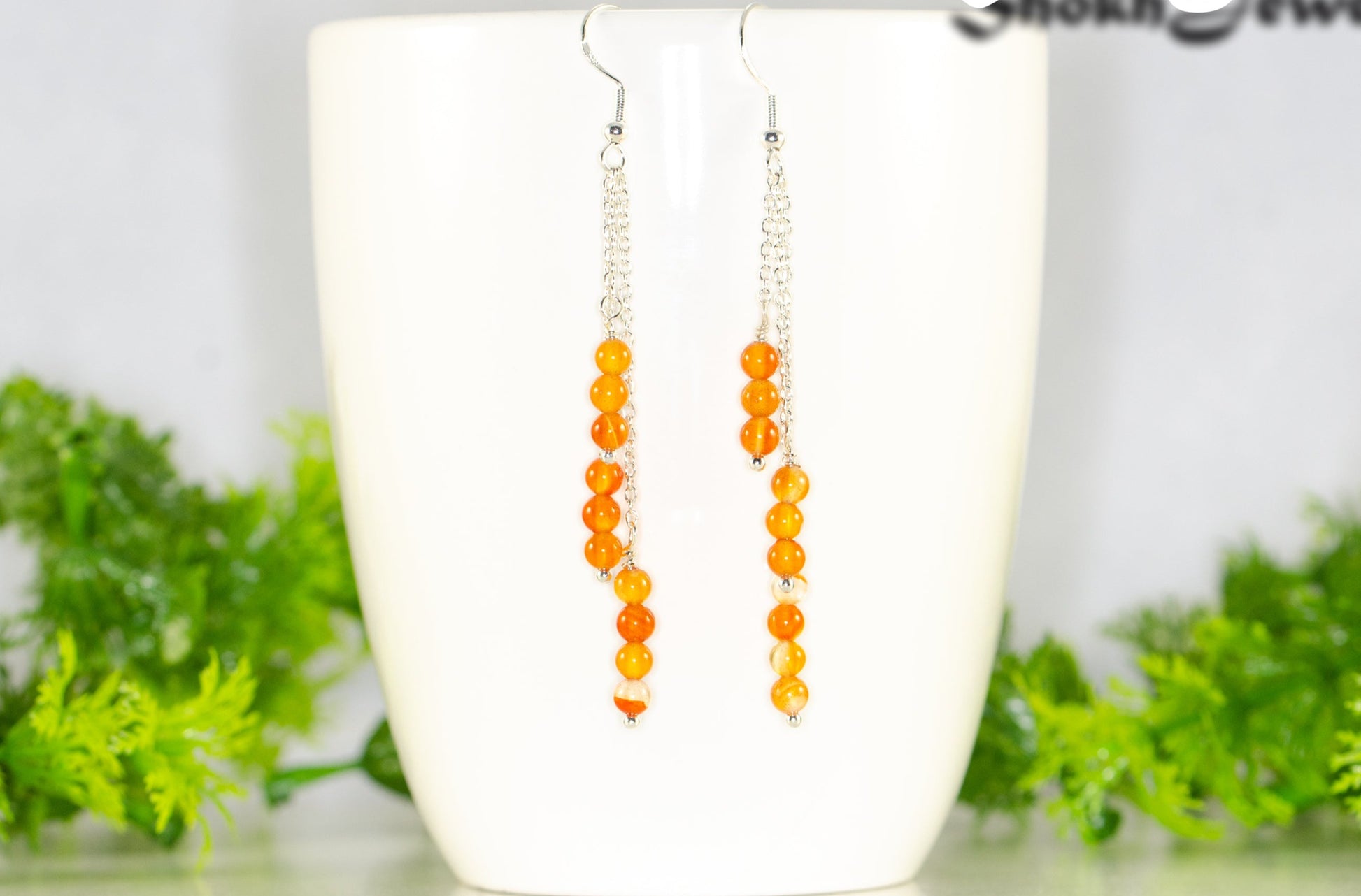 Silver Plated Chain and Carnelian Crystal Earrings displayed on a coffee mug.