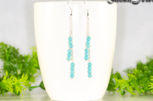 Silver Plated Chain and Turquoise Howlite Earrings displayed on a coffee mug.