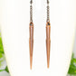 Close up of Long chain and antique copper spike earrings.