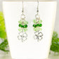 Lucky Four Leaf Clover Charm and Green Glass Bead Earrings displayed on a tea cup.