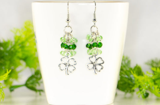Lucky Four Leaf Clover Charm and Green Glass Bead Earrings displayed on a tea cup.