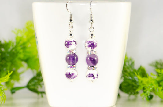 Long Floral Ceramic Bead and Amethyst Earrings displayed on a tea cup.