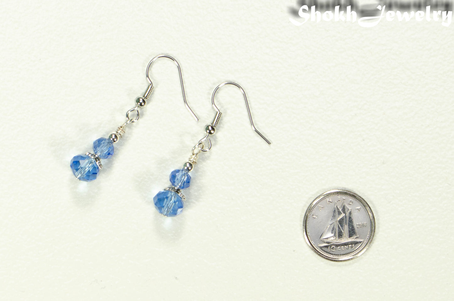 Small Light Blue Glass Bead Dangle Earrings beside a dime.