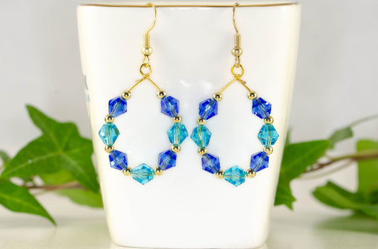 Blue Glass Crystal Hoop Earrings displayed on a tea cup.