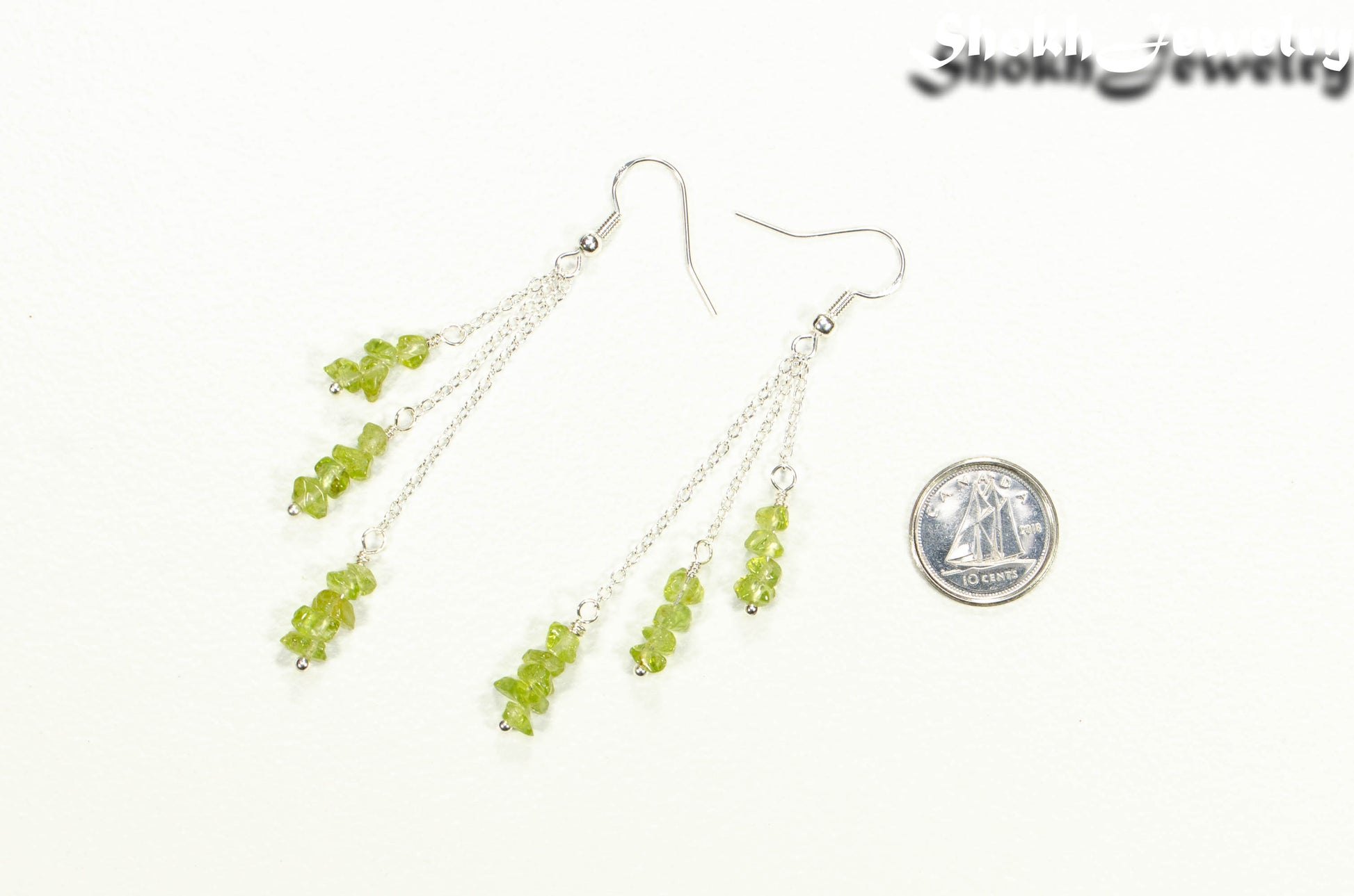 Long Silver Plated Chain and Peridot Chip Earrings beside a dime.