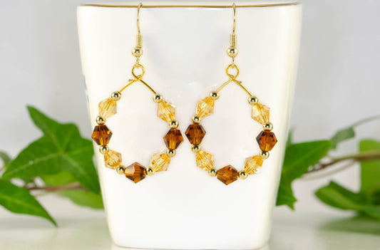 Amber and Brown Glass Crystal Hoop Earrings displayed on a tea cup.