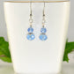 Small Light Blue Glass Bead Dangle Earrings displayed on a tea cup.