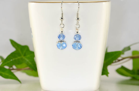 Small Light Blue Glass Bead Dangle Earrings displayed on a tea cup.
