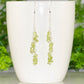 Long Silver Plated Chain and Peridot Chip Earrings displayed on a coffee mug.