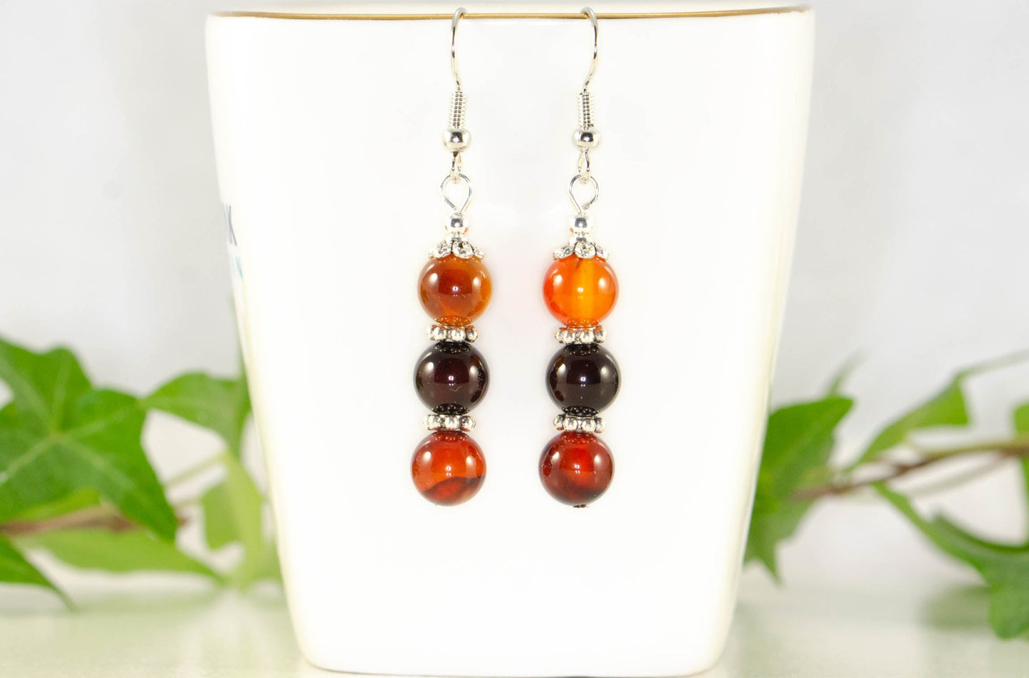 Natural Carnelian Beaded Bar Earrings displayed on a tea cup.