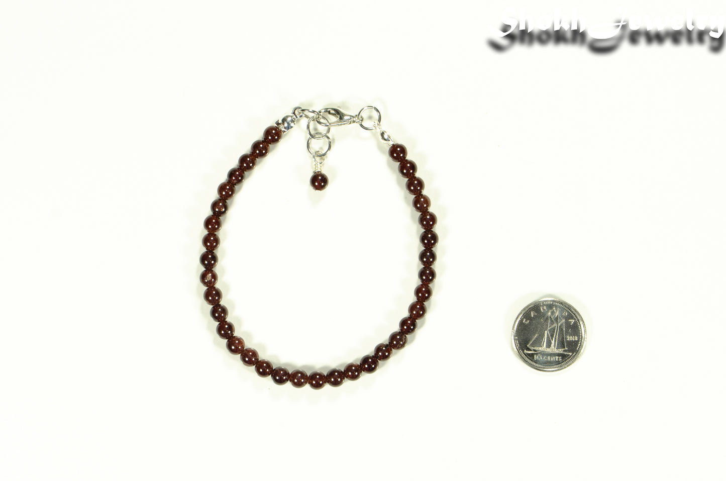 Dainty Garnet Bracelet with Clasp beside a dime.