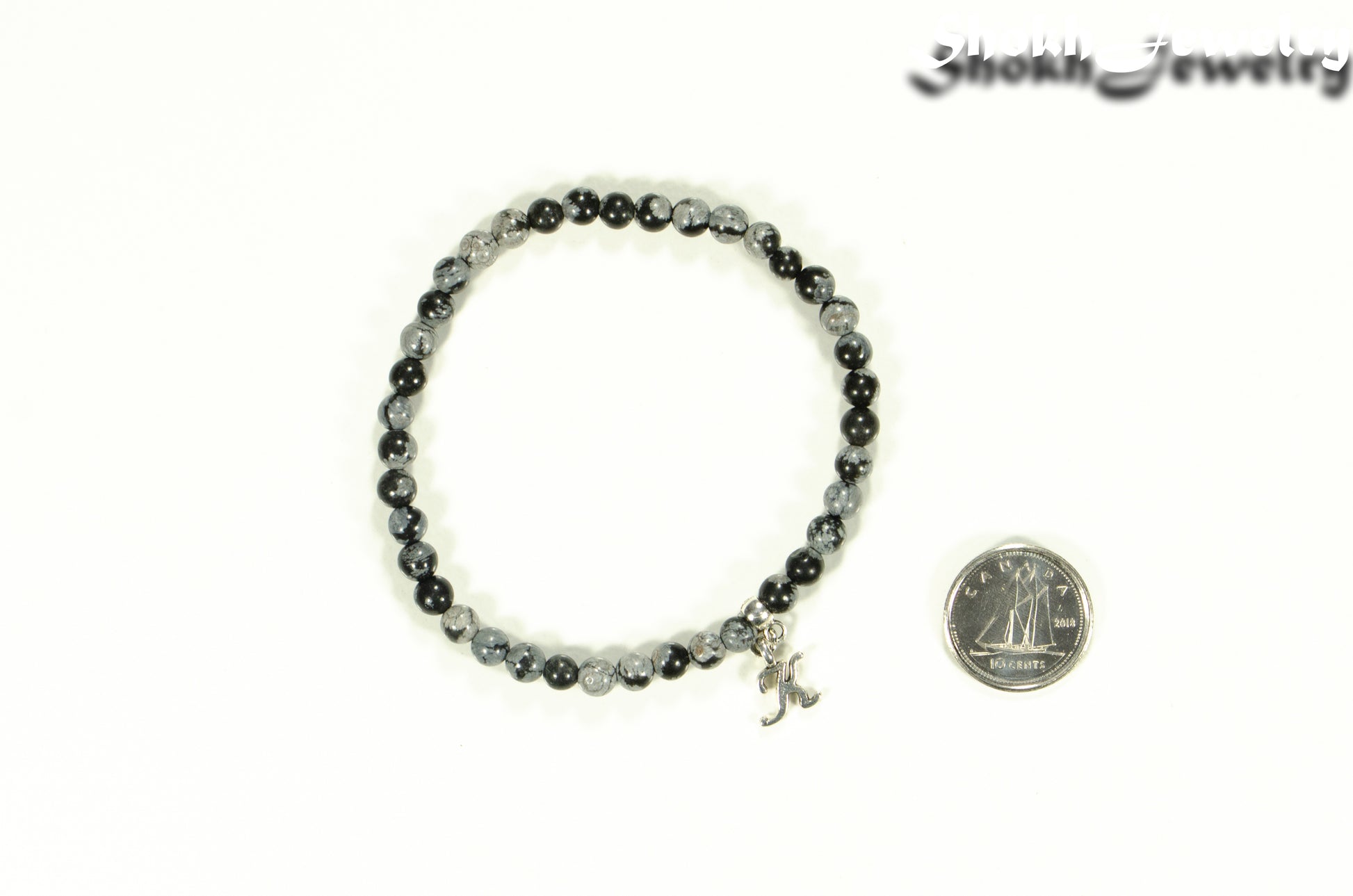 4mm Snowflake Obsidian Bracelet with Initial beside a dime.