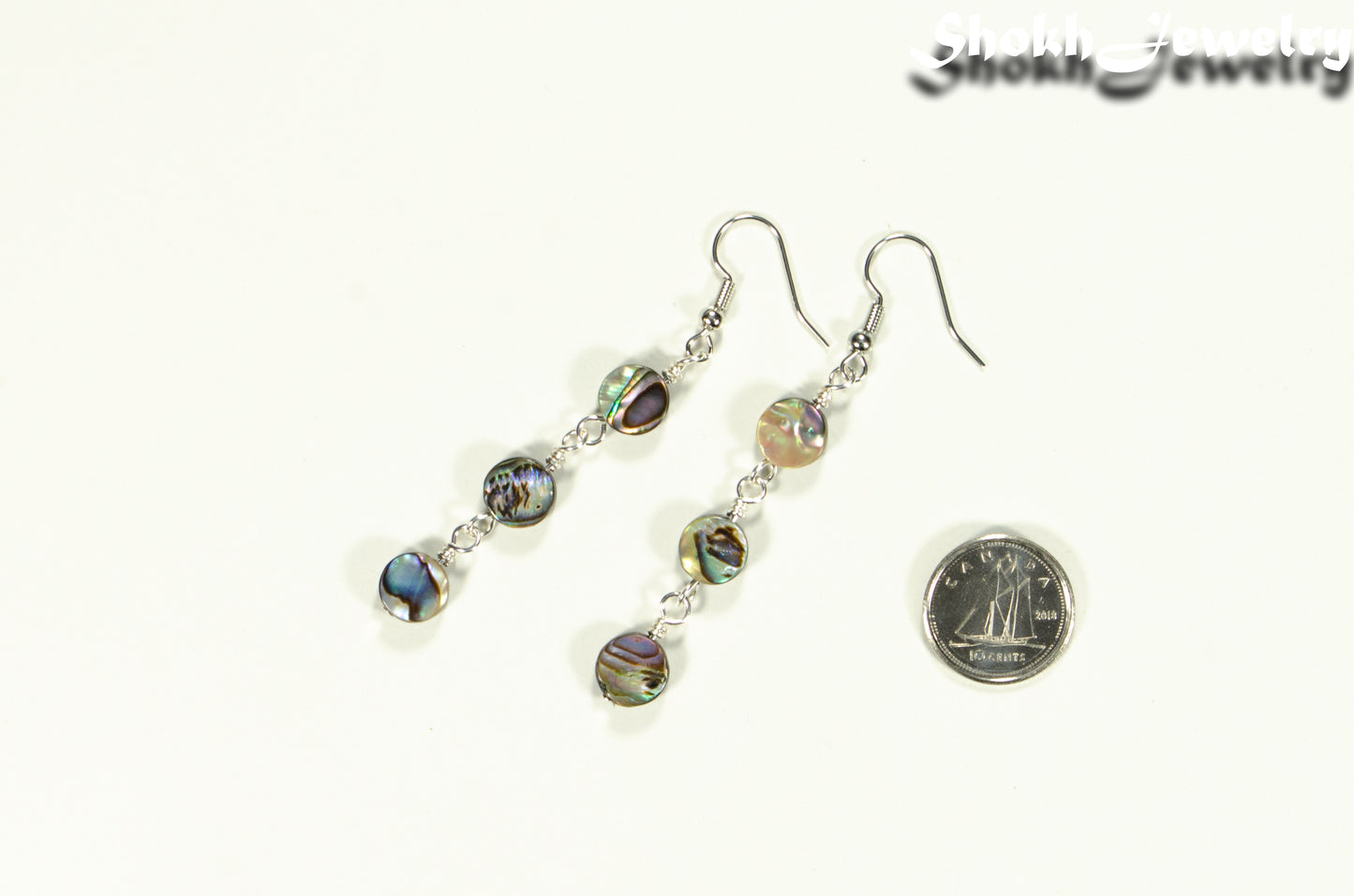 Elegant Long Natural Abalone Shell Earrings beside a dime.