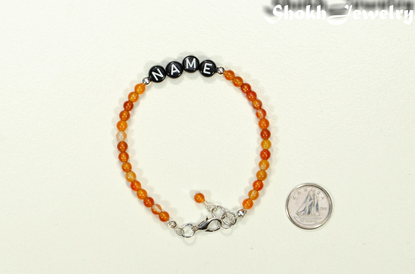 Personalized Carnelian Crystal Name Bracelet with Clasp beside a dime.