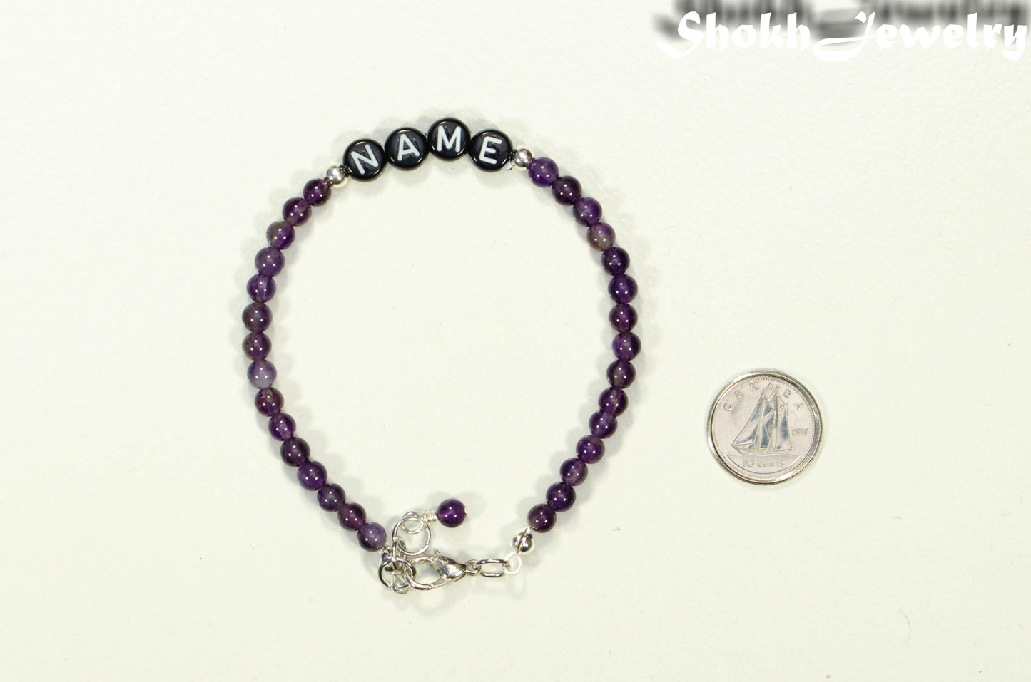 Personalized Amethyst Name Bracelet with Clasp beside a dime.