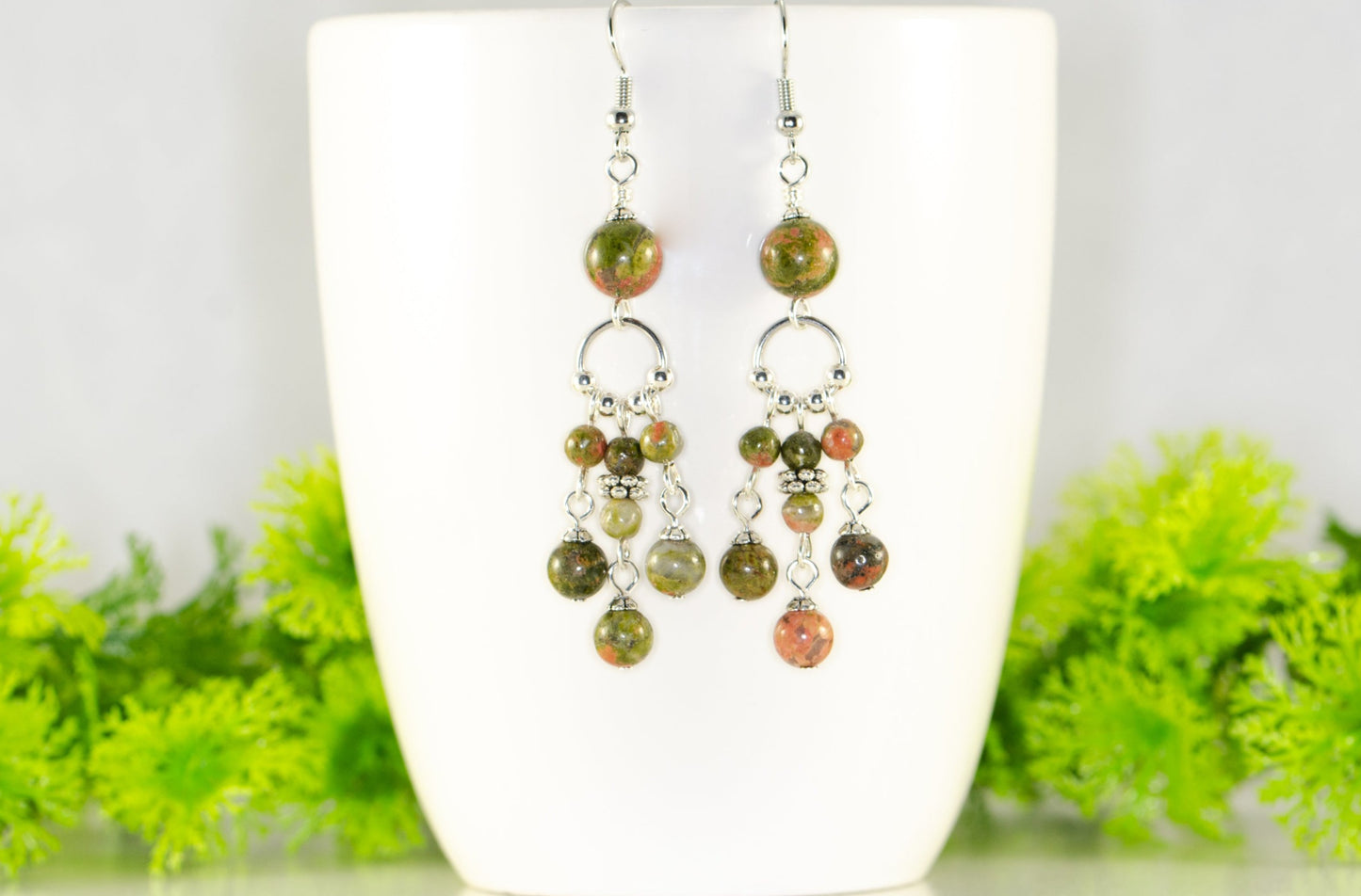 Statement Unakite Jasper Chandelier Earrings displayed on a coffee mug.