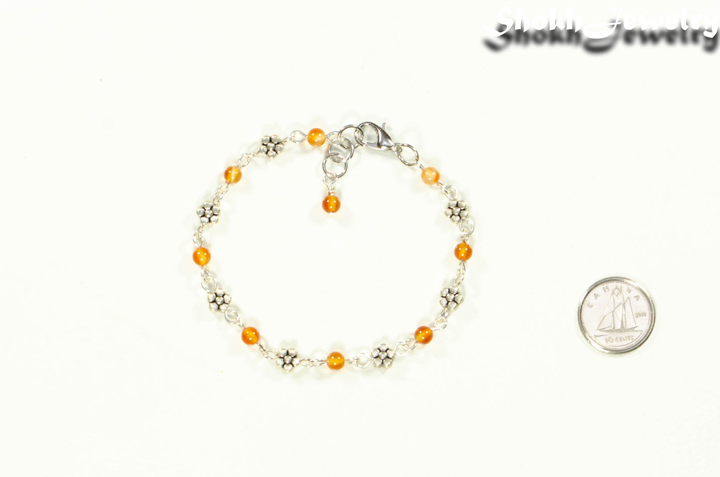 Tibetan Silver Flower and Carnelian Link Bracelet beside a dime.