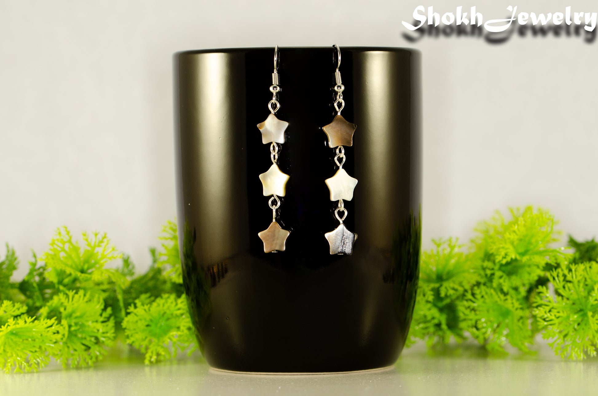 Long Natural Seashell Star Earrings displayed on a coffee mug.