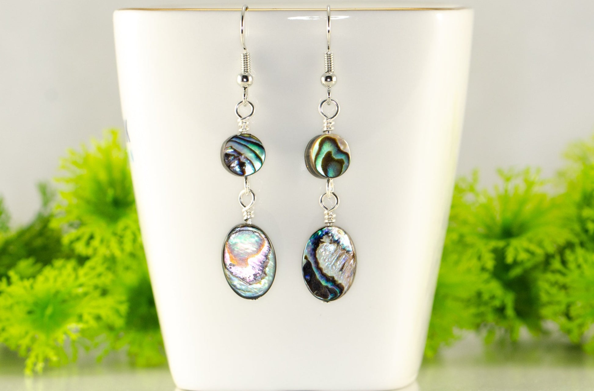 Elegant Long Oval Abalone Shell Earrings displayed on a tea cup.
