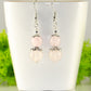 Natural Rose Quartz Crystal Dangle Earrings displayed on a tea cup.