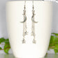 Long Crescent Moon and Hematite Star Earrings displayed on a coffee mug.