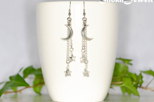 Long Crescent Moon and Hematite Star Earrings displayed on a coffee mug.