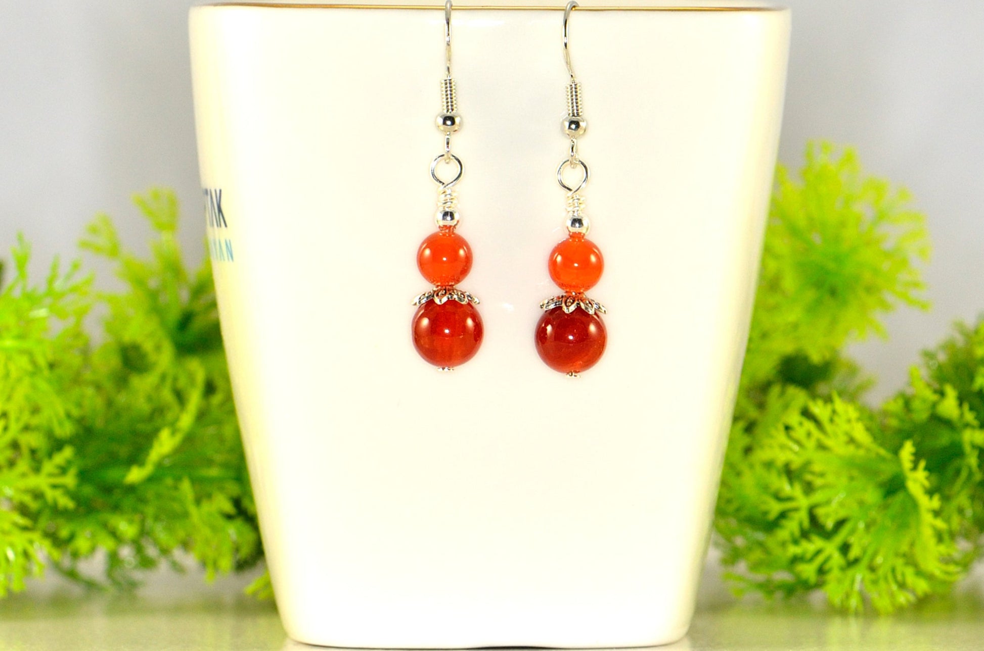 Small Natural Fire Agate Earrings displayed on a tea cup.