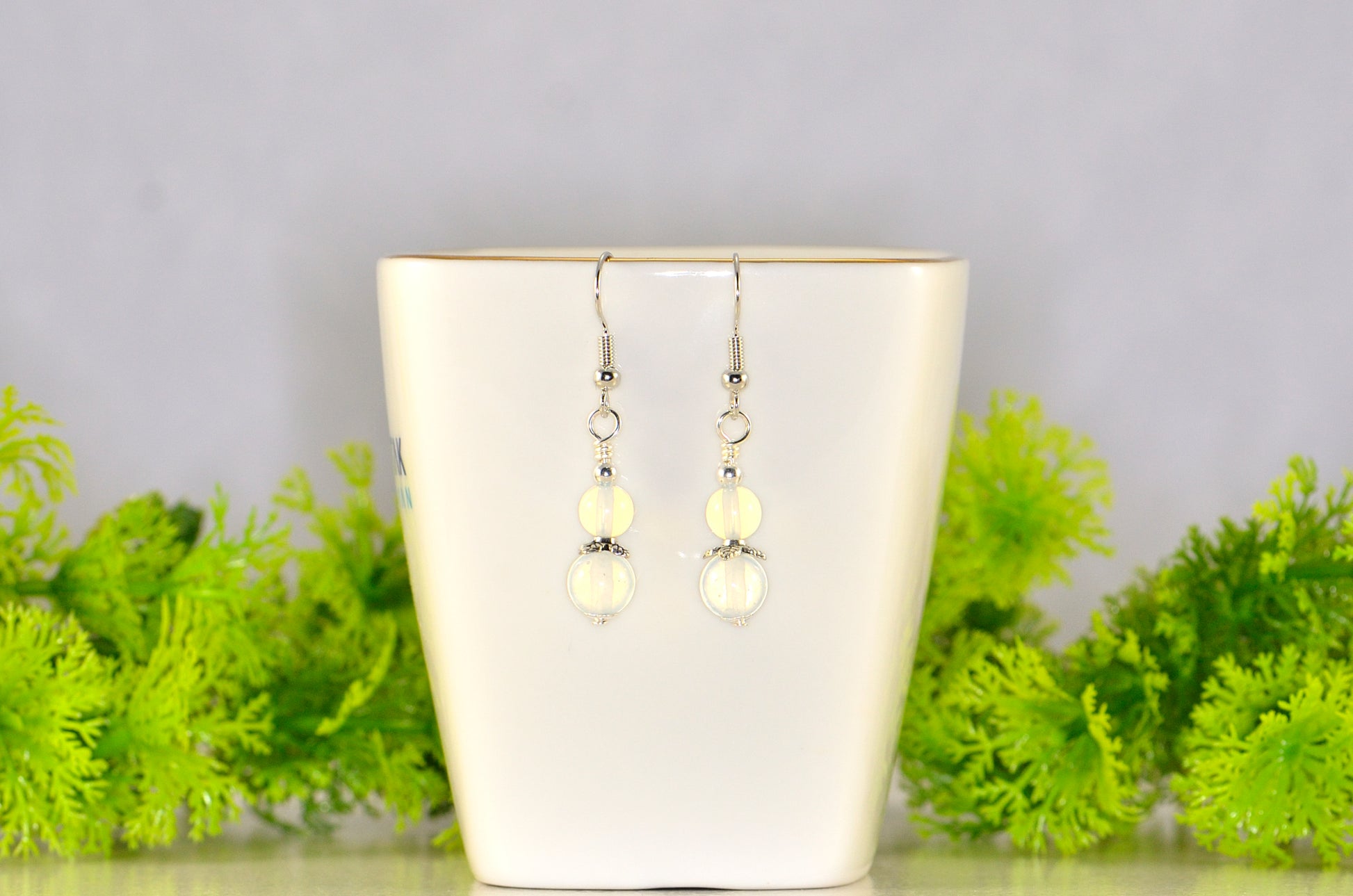 Small Opalite Crystal Earrings displayed on a tea up.