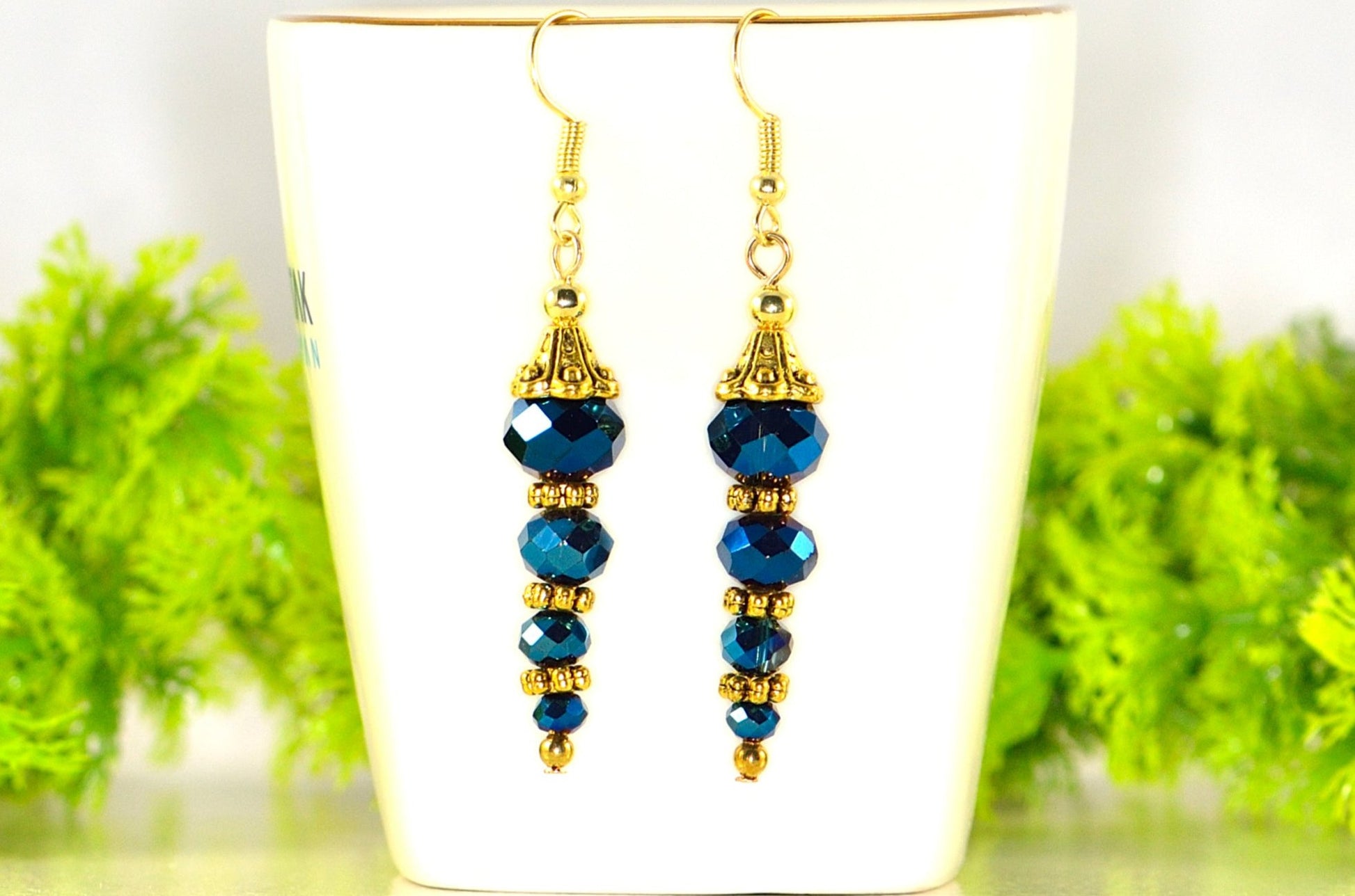 Sparkly Blue Glass Crystal Bead Earrings displayed on a tea cup.