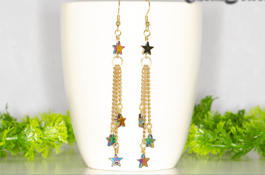 Sparkly Hematite Star and Gold Chain Earrings displayed on a white mug.