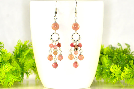 Statement Pink Rhodonite Chandelier Earrings displayed on a coffee mug.